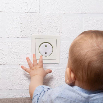 Bébé curieux touche cache prise au mur
