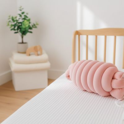 Tresse de lit bébé rose déposé sur le lit